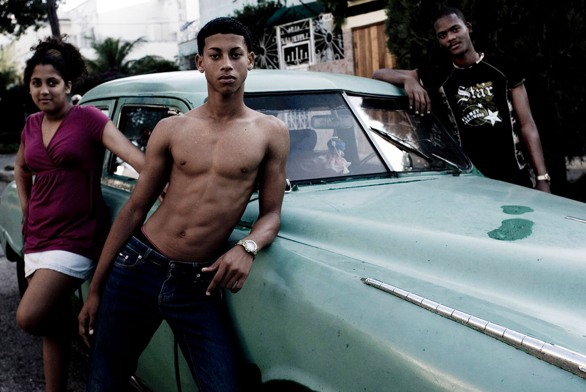 Des adolescents de La Havane. Derriere, une vieille voiture des annees 50.